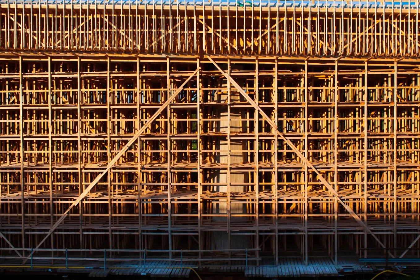 Intricate wooden scaffolding structure for bridge construction lit by the setting sun