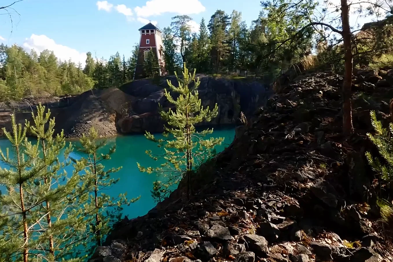 A view of the turquoise water in the old mine quarry surrounded by rocky cliffs and trees